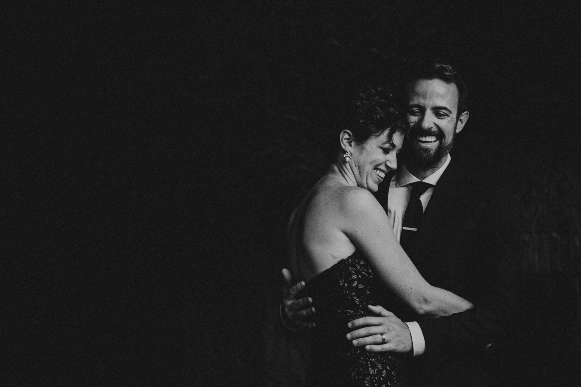 bride wearing black dress is laughing with the groom
